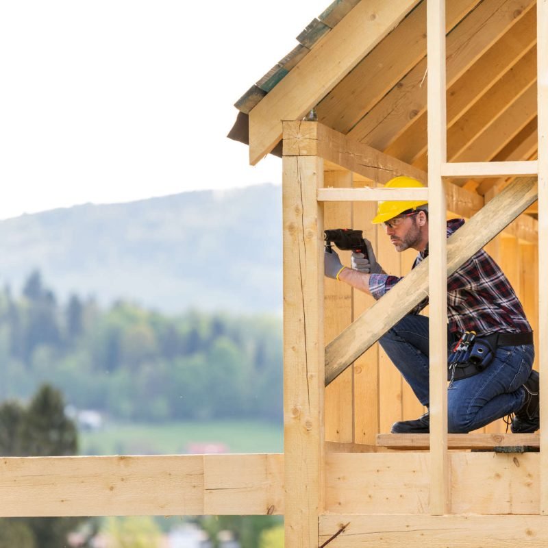 roofer-builder-working-on-roof-structure-at-constr-6AHKKP3.jpg